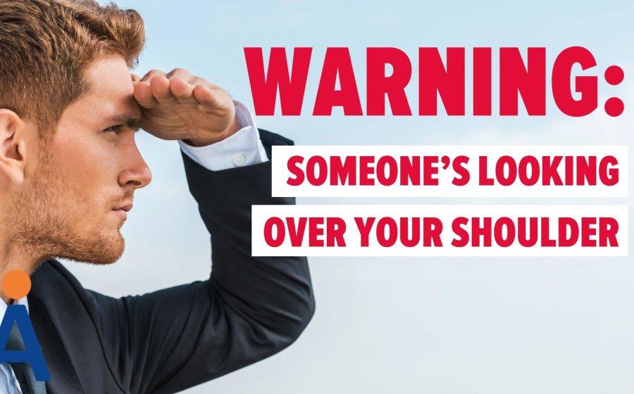 A man in a suit looks into the distance with his hand above his eyes. Bold red and white text reads: WARNING: ONLOOKER DETECTION—SOMEONES LOOKING OVER YOUR SHOULDER. An abstract logo appears in the corner.