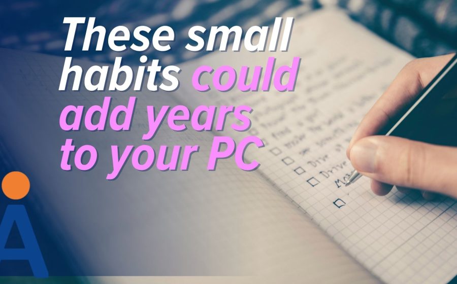 A hand writes in a notebook with checkboxes, while text over the image reads: These small habits could be key to adding years to your PC's life. A blue logo with an orange dot appears in the bottom left corner.