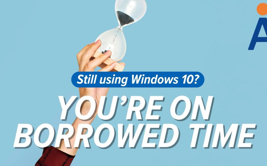 A hand holds an hourglass against a blue background. Text reads: Still using Windows 10? YOU’RE ON BORROWED TIME—Windows 10 extended support ends in October 2026. A stylized A logo appears in the top right corner.